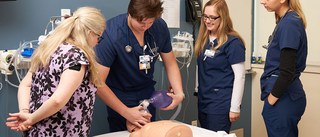 Healthcare professionals practicing emergency medical procedures on a patient simulator mannequin.