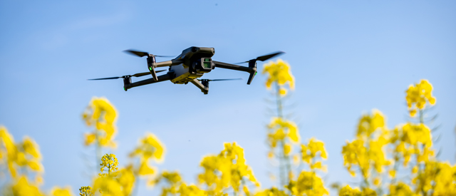 a drone with a camera flying over crops.