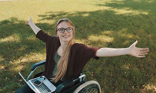 a student sitting in a wheel chair with her arms outstretched.