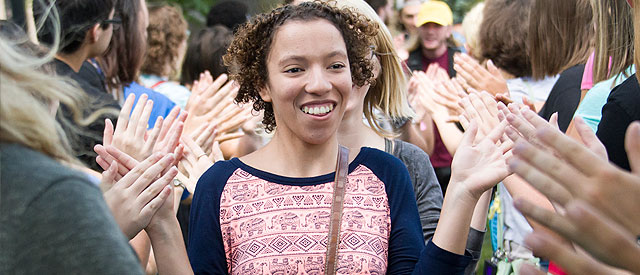 Joyful woman walking through a clapping crowd, feeling celebrated and supported.
